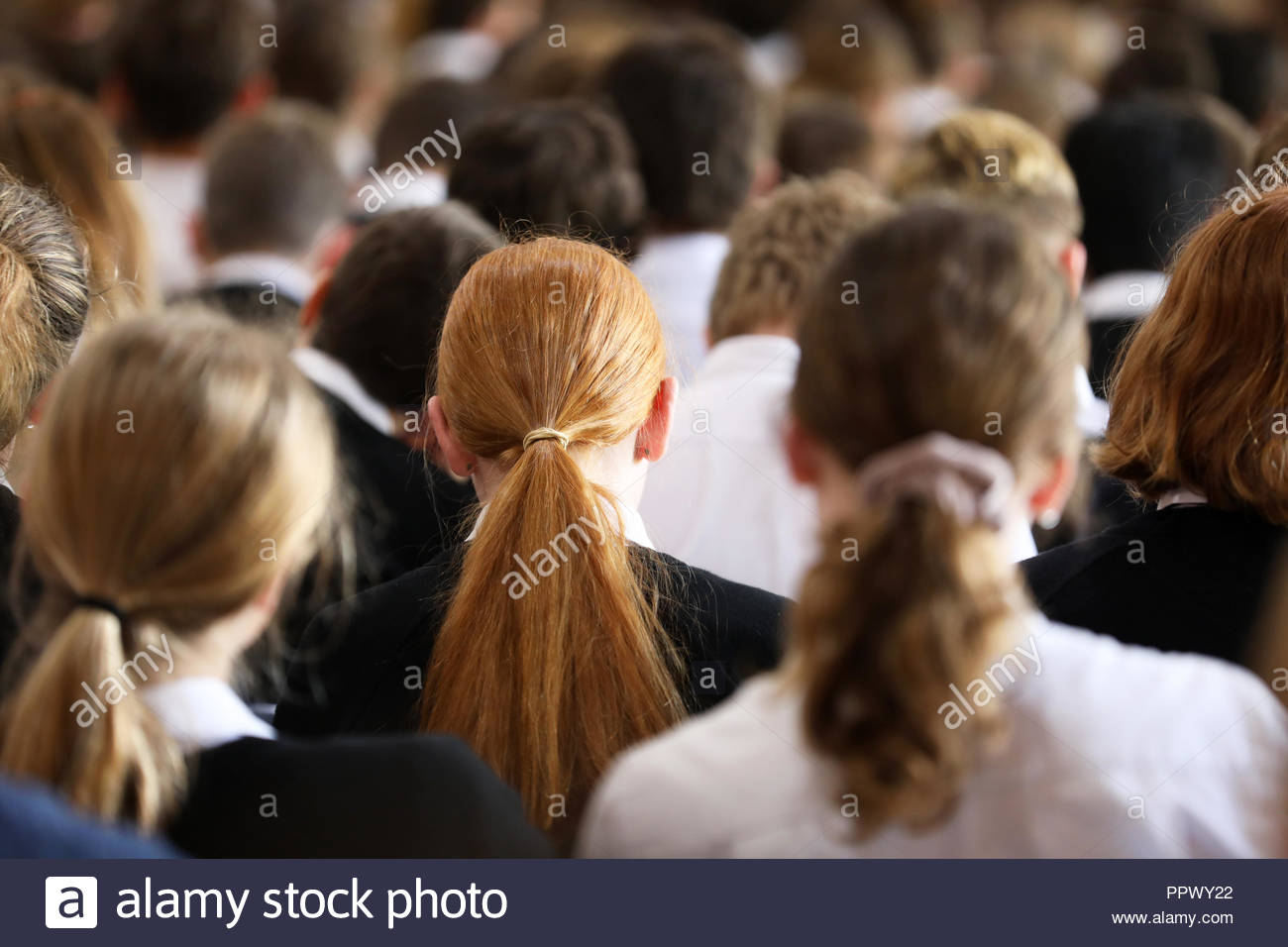 Crowd Of High School Students In Uniform At Assembly Listening And