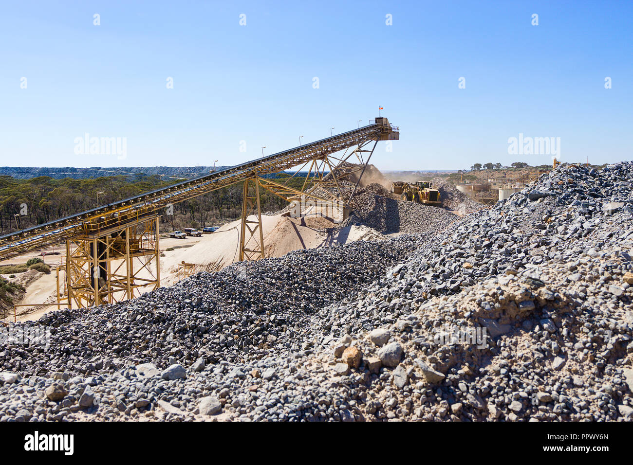 Crushed ore stock pile and feeder at mine site processing plant Stock Photo