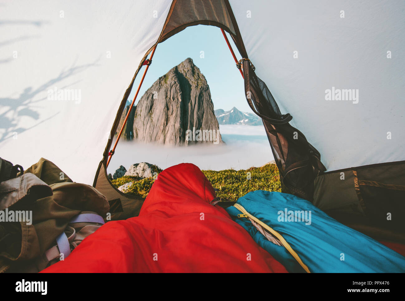Couple in sleeping bags enjoying mountain view from camping tent travel enjoying vacations adventure lifestyle good morning outdoor in Norway Stock Photo