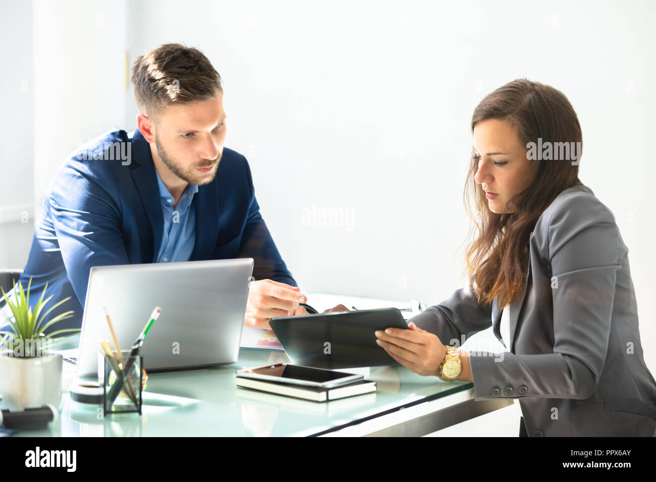 Two Young Businesspeople Using Digital Tablet At Workplace Stock Photo