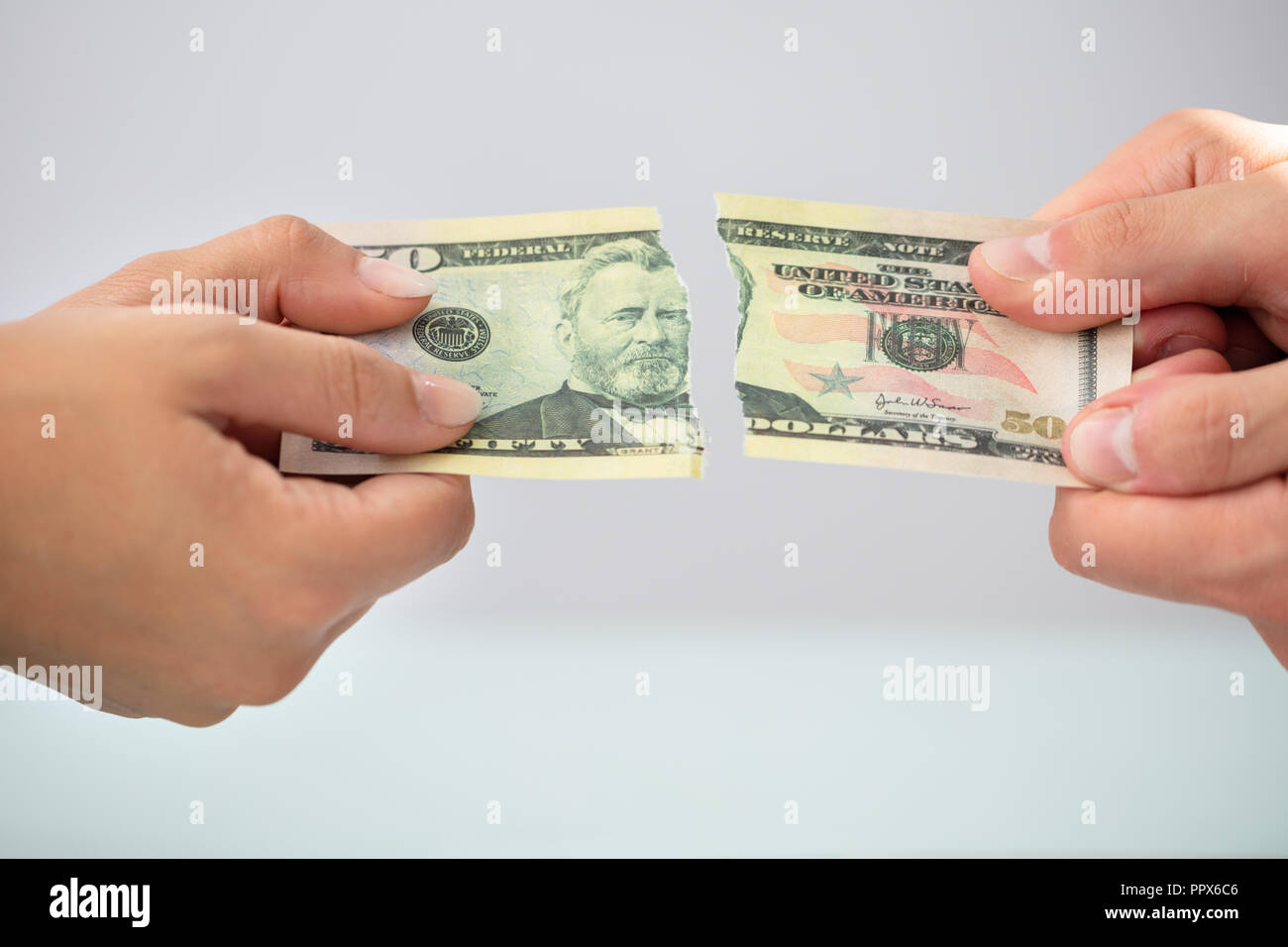 Close-up Of Two Businesspeople Hands Holding Torn American Banknote Stock Photo