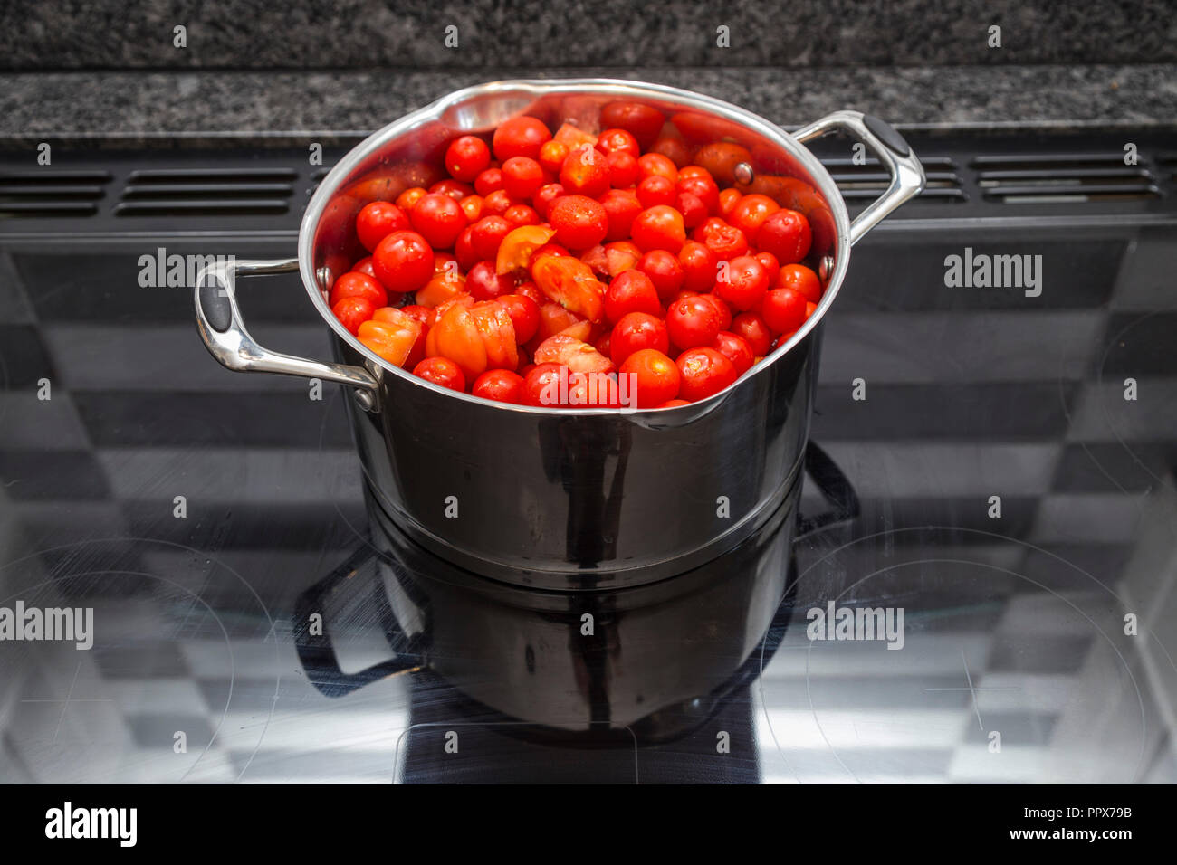A large pan full of tomatoes on an induction hob ready to make tomato soup Stock Photo
