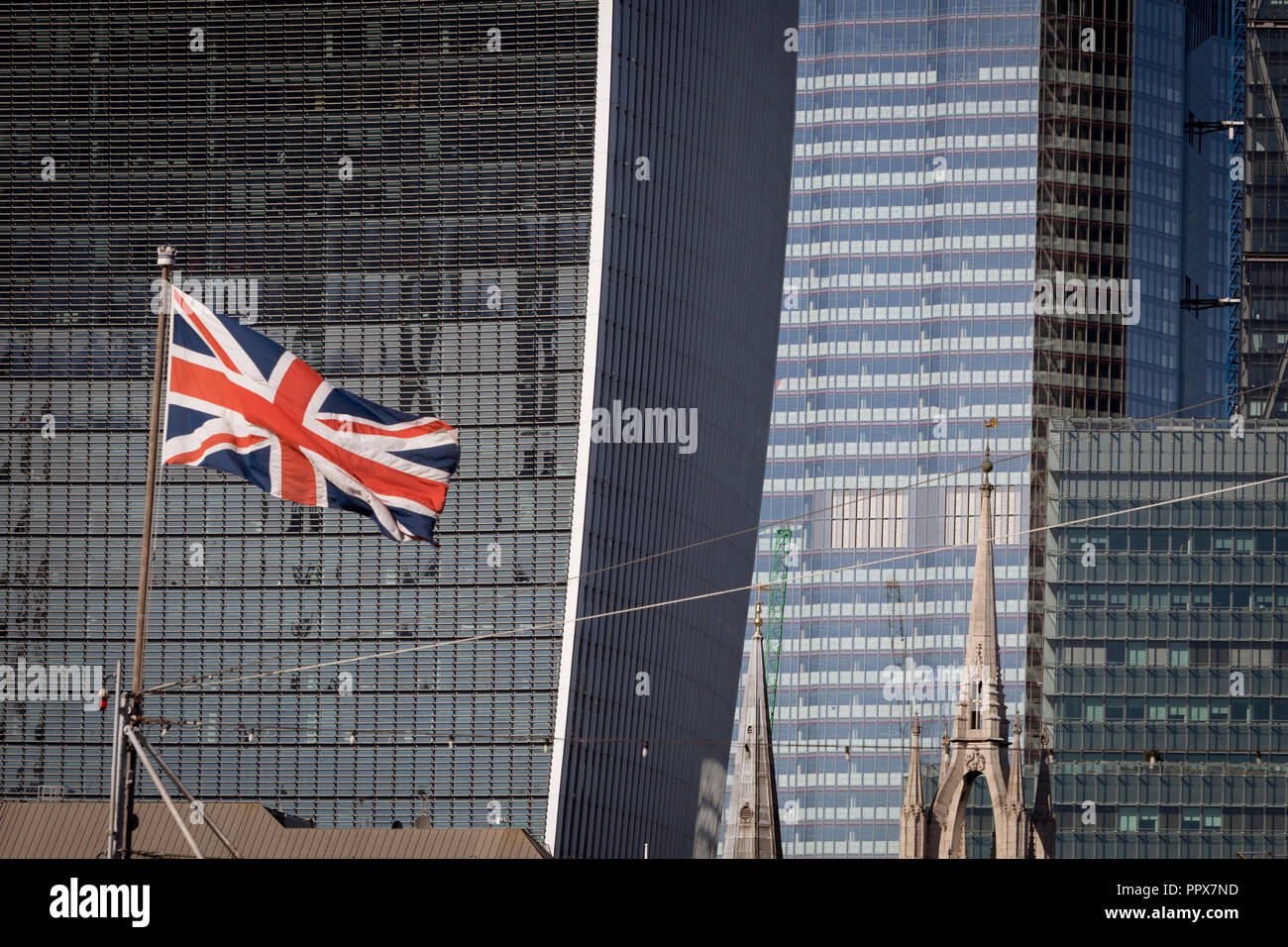 Seen from the south bank of the river Thames, a Union Jack flag flies on the bow of WW2 battleship HMS Belfast with the City of London - the capital's financial centre (aka The Square Mile) in the background, on 27th September 2018, in London, England. Stock Photo