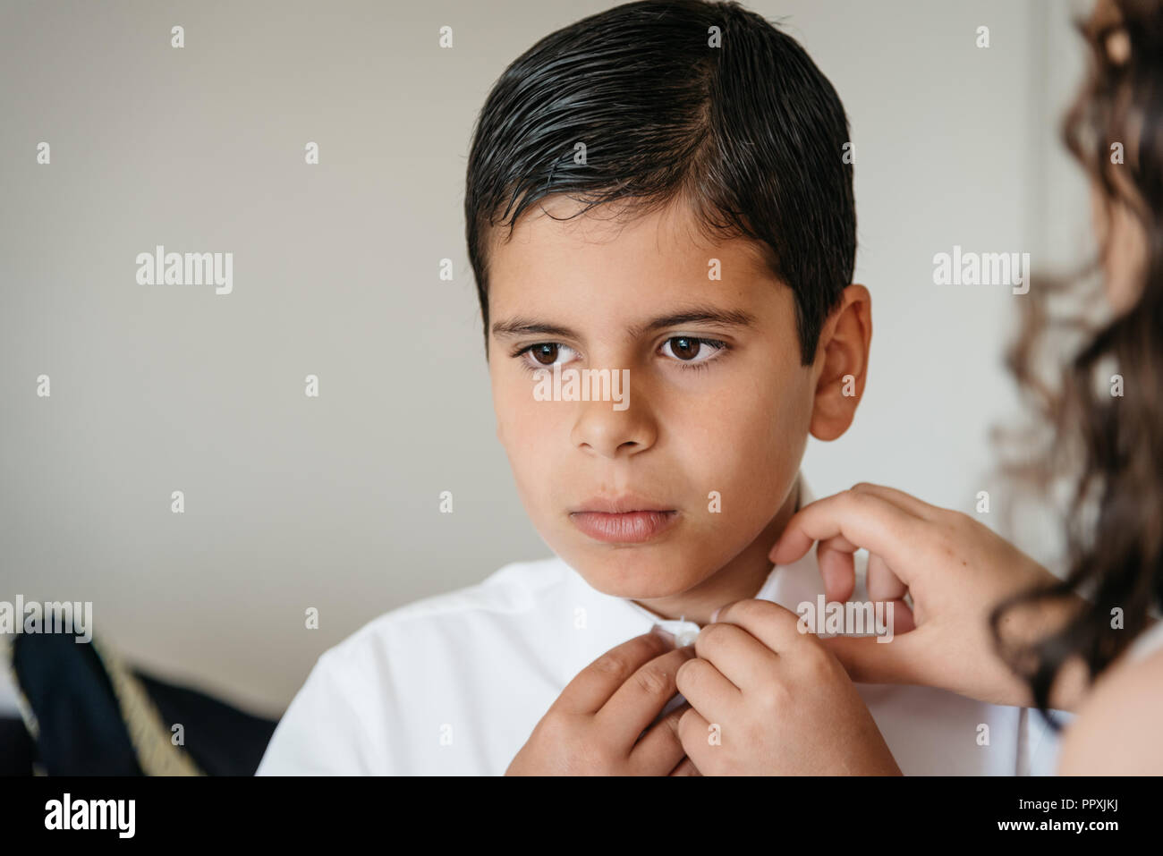 Young boy getting ready for celebration. Her sister is helping him Stock Photo