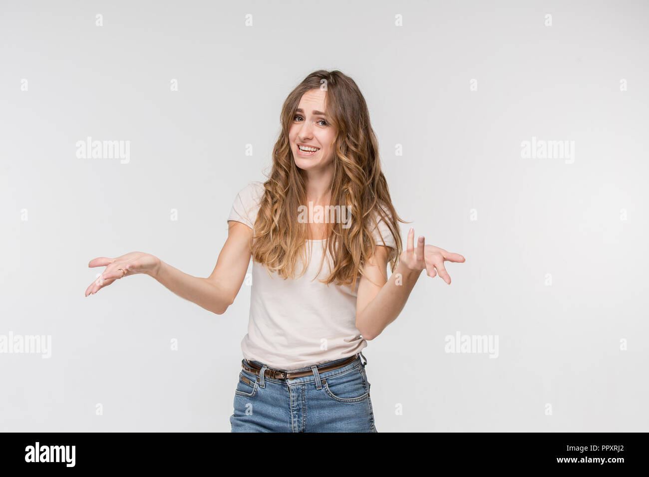 Why is that. Beautiful female half-length portrait isolated on white studio backgroud. Young emotional surprised, frustrated and bewildered woman. Human emotions, facial expression concept. Stock Photo
