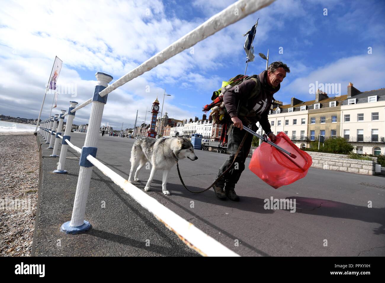 Wayne Dixon, 47, halfway through his journey to collect litter along the whole coast of Britain. Presently in Weymouth and is raising money for charities MIND and the Northern Inuit Dog Society. He is completing his challenge with his dog Koda, a Northern Inuit, and says he is ‘fulfilling a lifelong dream by walking the coast of Britain.’ “I am picking up litter across the whole coast of Britain. I pick up every piece of litter I walk past.  Credit: Finnbarr Webster/Alamy Live News Stock Photo