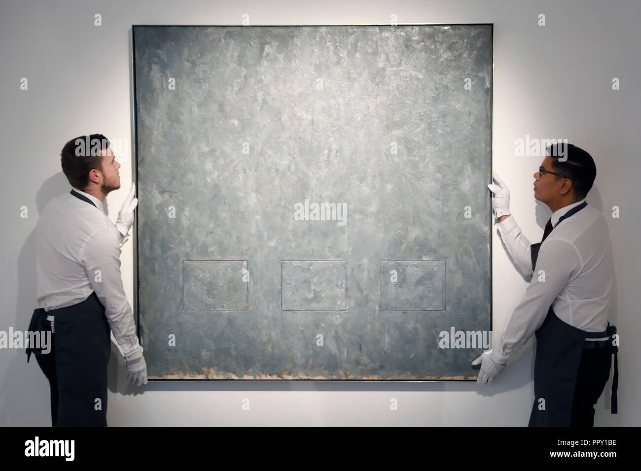 London, UK. 28th Sep 2018. Christie's employees pose with artist Jasper Johns work 'Gray Rectangles' at Christie's auction house in London, Friday September 28, 2018.  It is expected to achieve up to $30million when it comes to sale in New York in November. Photograph : © Luke MacGregor Credit: Luke MacGregor/Alamy Live News Stock Photo