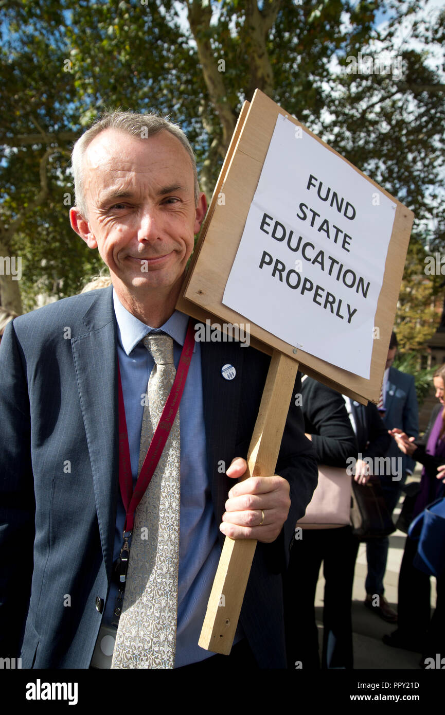 Westminster. London, UK. September 28th 2018. Headteachers from all over the country demonstrated in Parliament Square over cuts to state school funding and walked to Downing Street where they handed in a letter to the Chancellor of the Exchequer, Philip Hammond. A headteacher holds a placard saying 'Fund state education properly'. Credit: Jenny Matthews/Alamy Live News Stock Photo