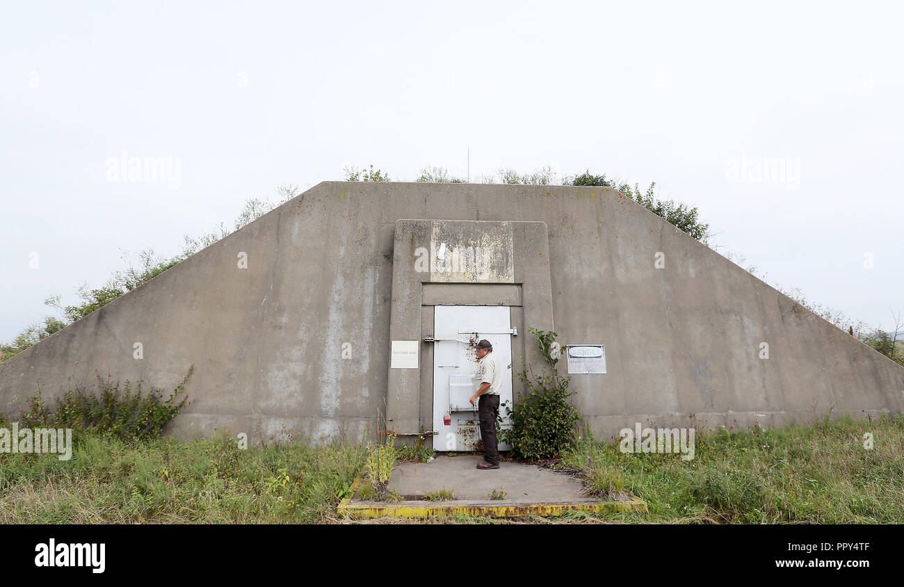 September 20, 2018 - Savanna Army Depot, Iowa, U.S. - Wildlife Refuge Specialist Alan Anderson opens the door of one of the 409 remaining â€œigloos,â€ steel reinforced cement bunkers shaped like domed ice igloos used to store ordnance (bombs). Each unit with a single vertical face for the massive steel door. The igloos ranged in size from about 1,100 to 1,800 square feet of floor space. Bulldozers plowed two feet of topsoil up over the sloping sides and roof, and grasses were planted over the tops to obscure the visibility from the air. One igloo blew up in 1948, leaving a crater 100 feet wid Stock Photo