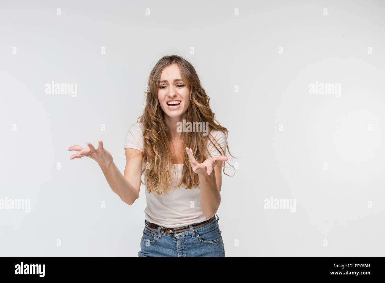 Why is that. Beautiful female half-length portrait isolated on white studio backgroud. Young emotional surprised, frustrated and bewildered woman. Human emotions, facial expression concept. Stock Photo