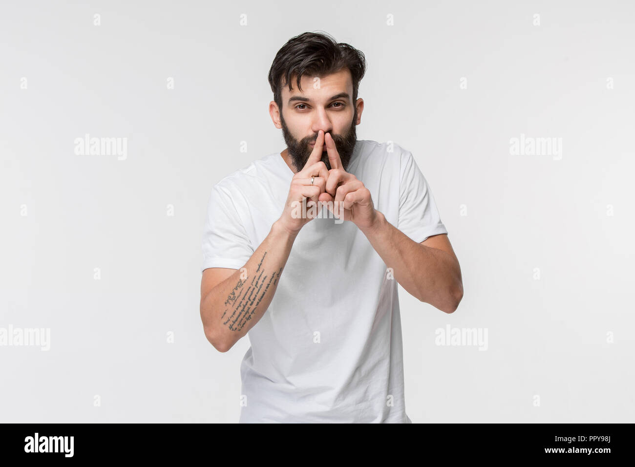 Secret, gossip concept. Young man whispering a secret behind his hand. Businessman isolated on white studio background. Young emotional man. Human emotions, facial expression concept. Stock Photo