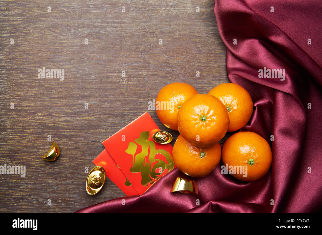 Chinese New Year decoration on wooden table - Gold sycee (Foreign text means wealth) and red packet (Foreign text means prosperity) Stock Photo
