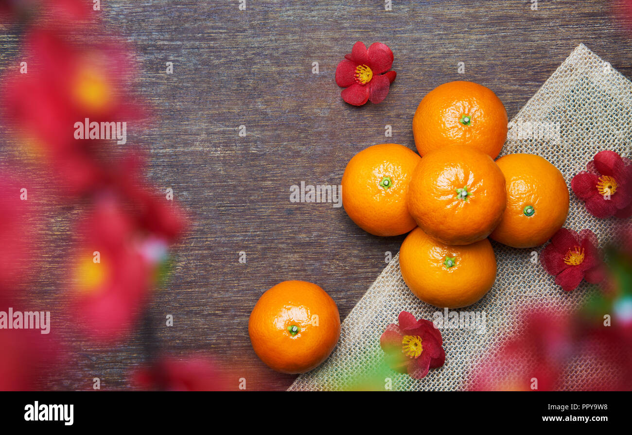 Chinese New Year - Mandarin oranges on wooden table with flower foreground Stock Photo