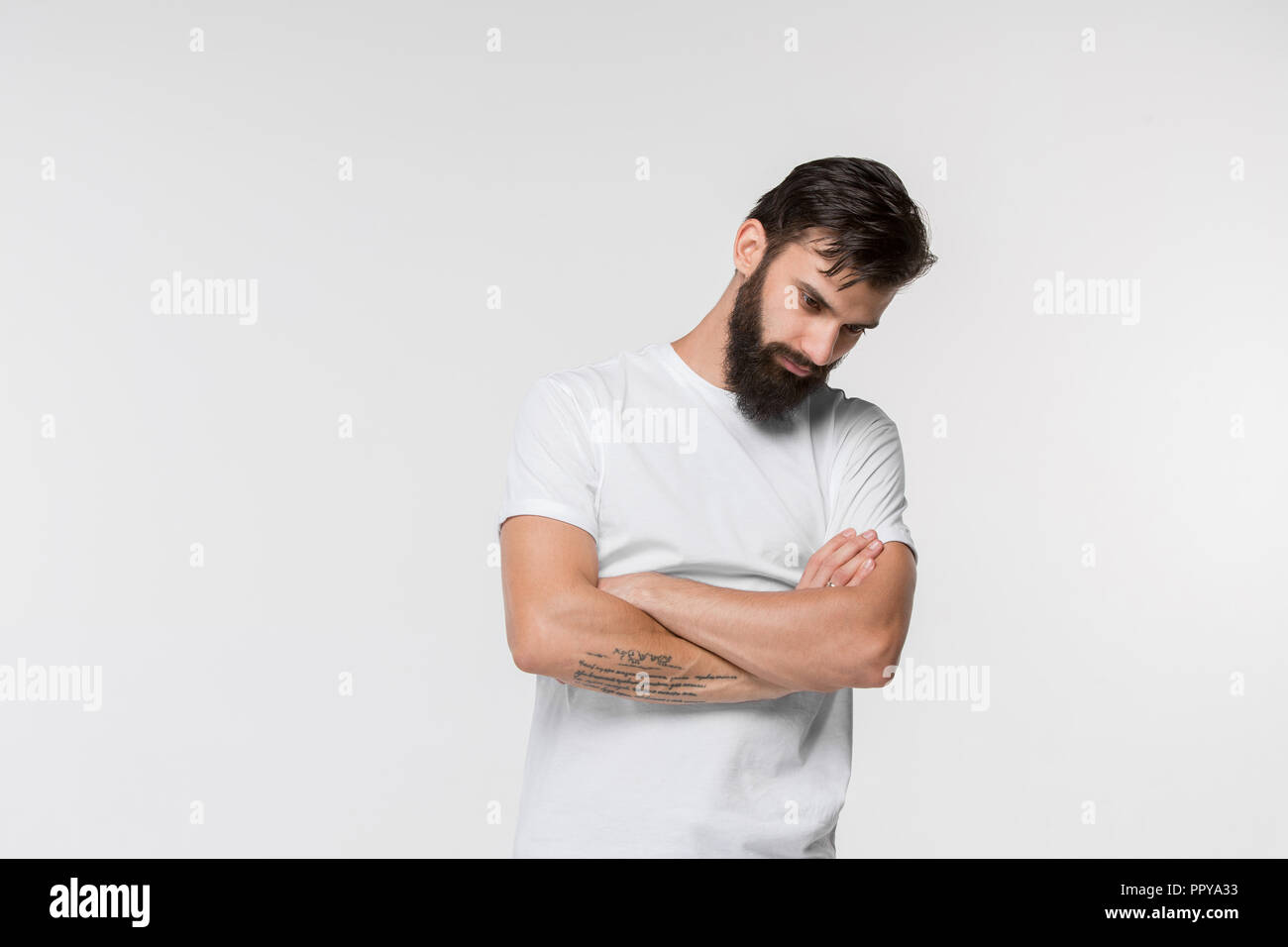 Why is that. Beautiful male half-length portrait isolated on white studio backgroud. Young emotional frustrated and bewildered man. Human emotions, facial expression concept. Stock Photo