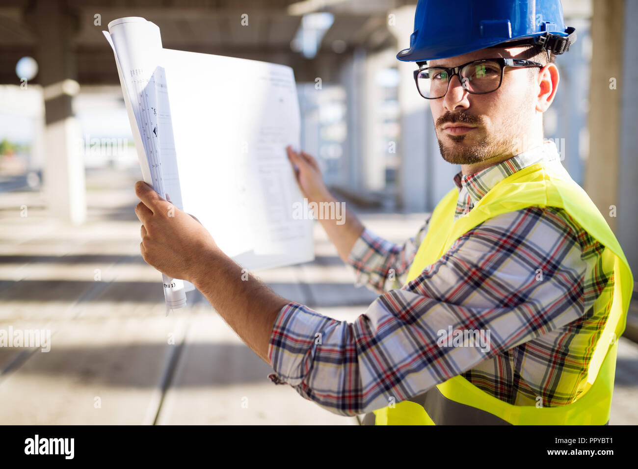 Engineer working on construction site and holding blueprint Stock Photo ...