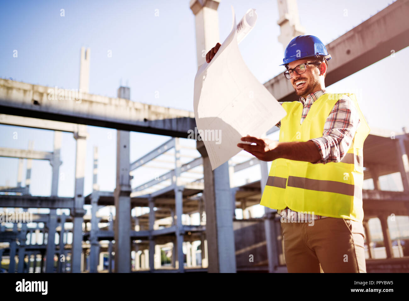 Engineer working on construction site and holding blueprint Stock Photo ...