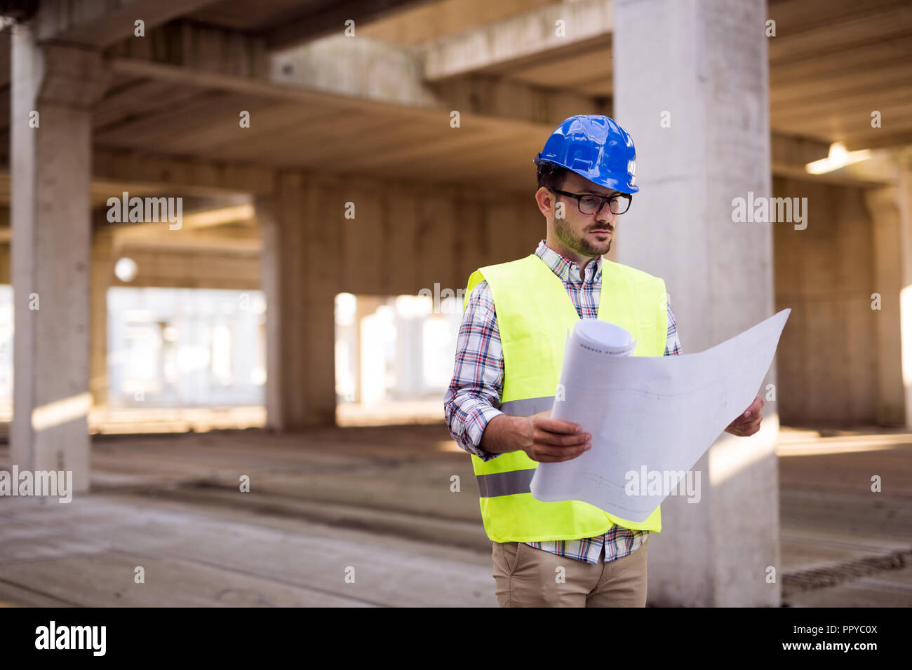 Engineer working on construction site and holding blueprint Stock Photo ...