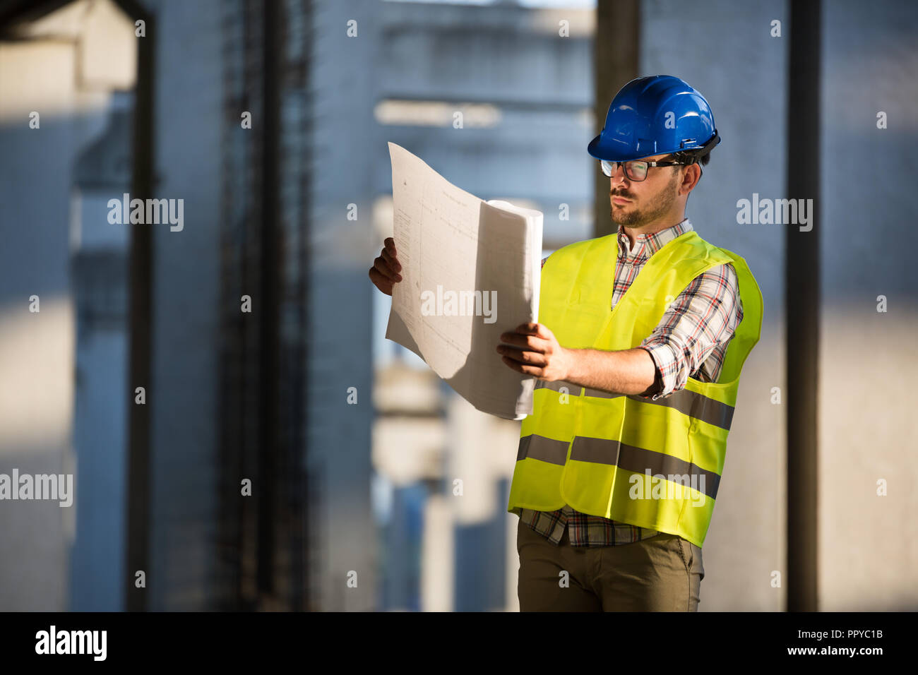 Engineer working on construction site and holding blueprint Stock Photo ...