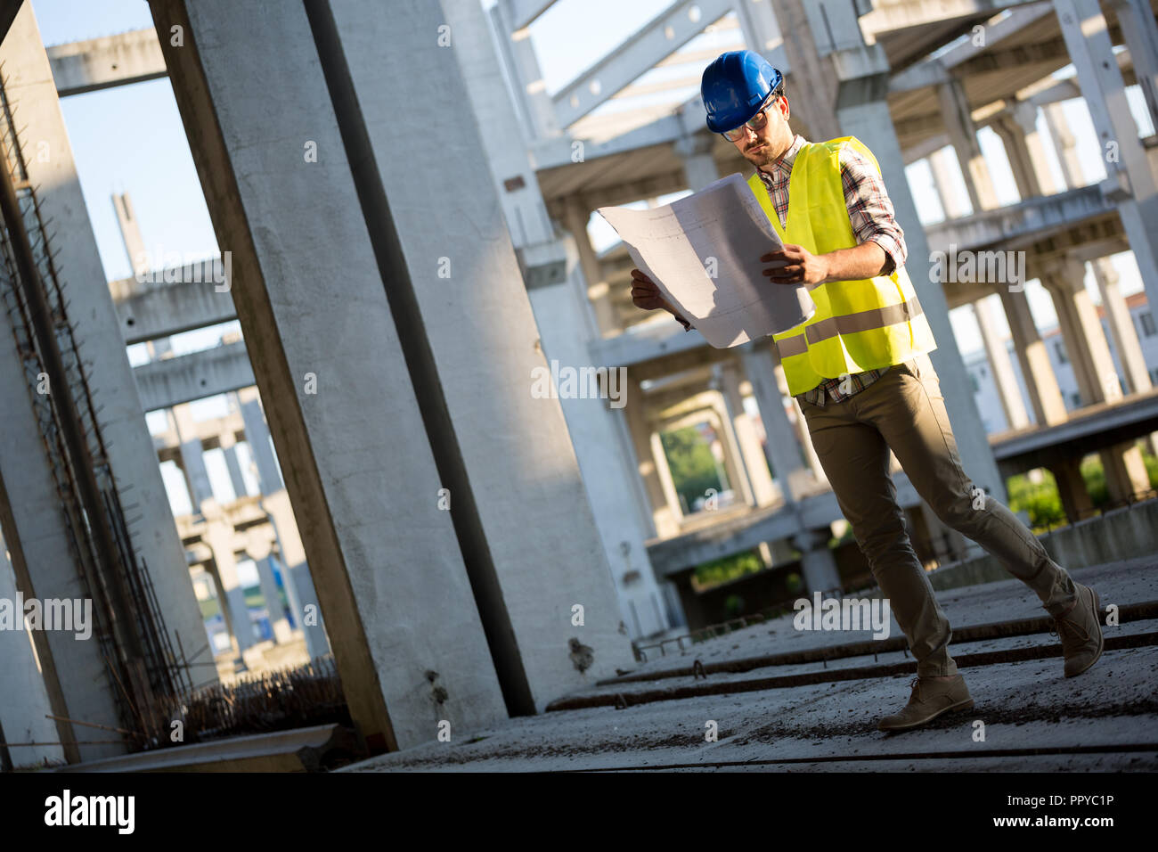 Engineer working on construction site and holding blueprint Stock Photo ...