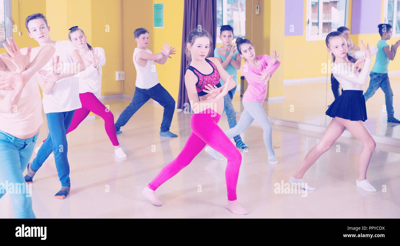 teenage-boys-and-girls-practicing-dance-stretching-with-female-trainer