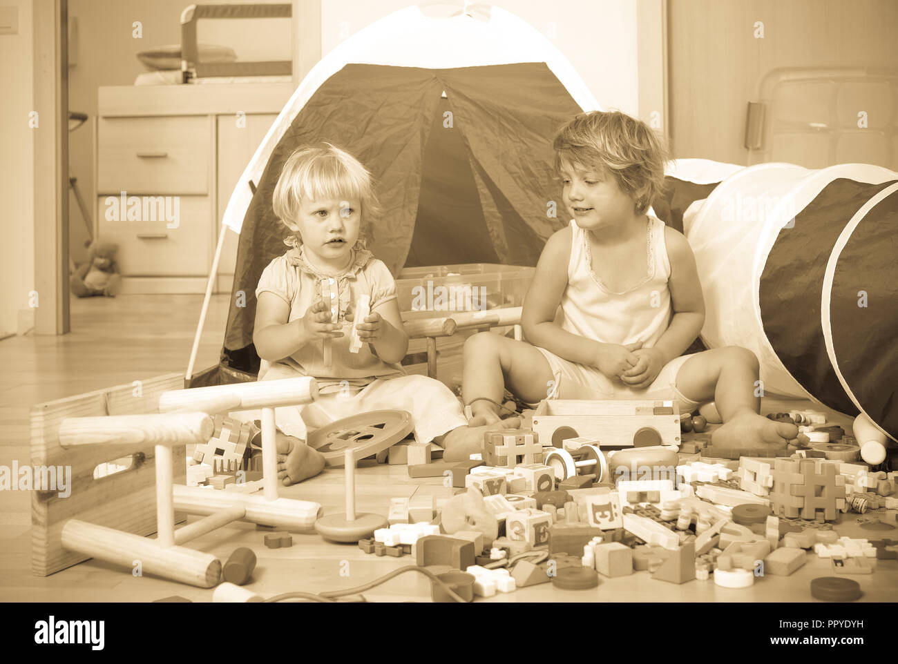 Two siblings together playing with toys indoor Stock Photo - Alamy