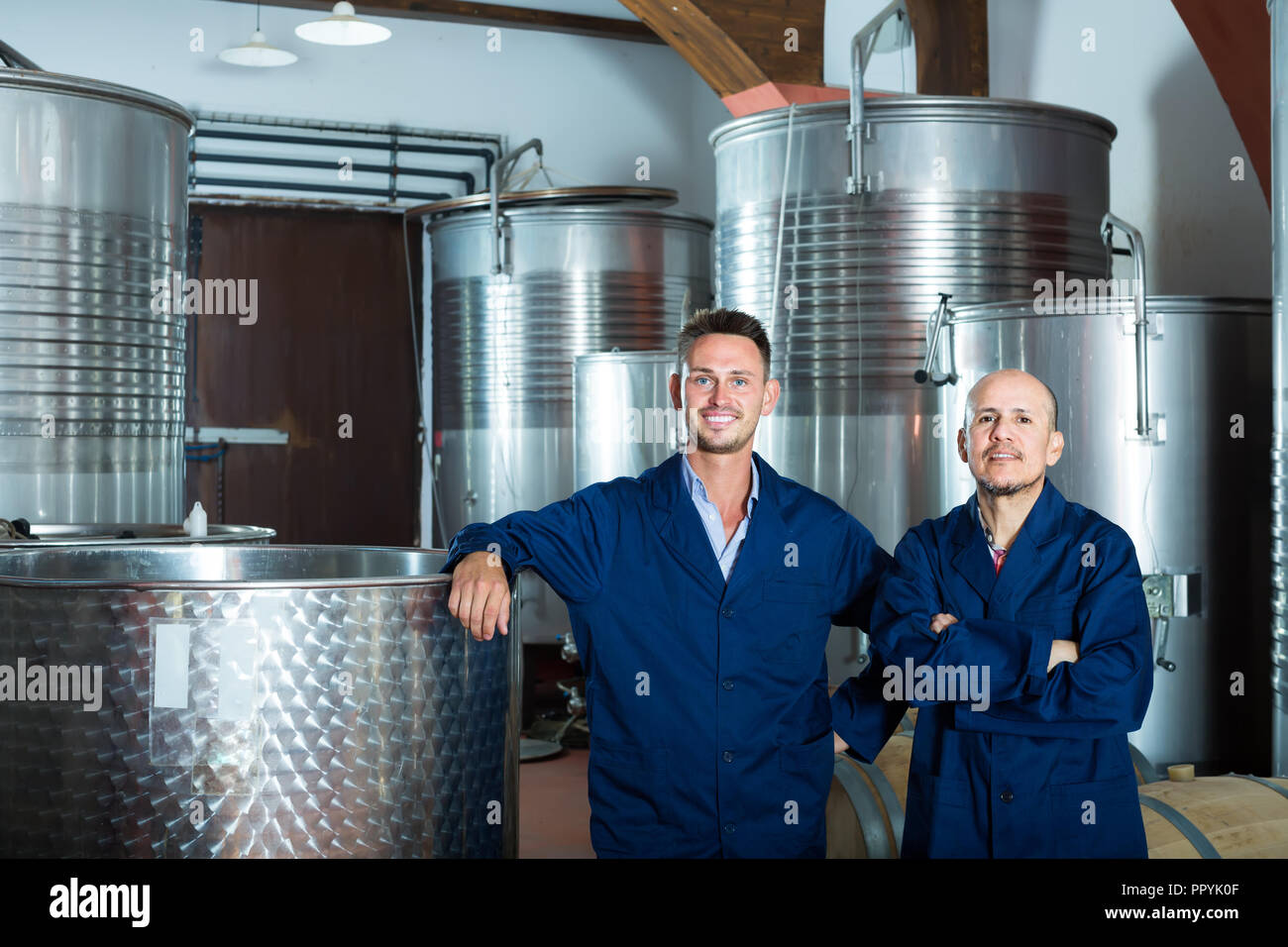 Two cheerful men professionals in uniforms standing in winery