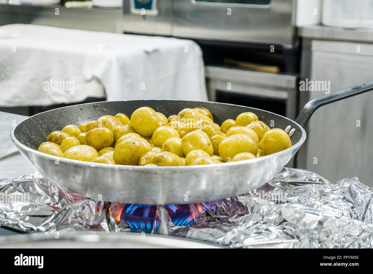 Many small potatoes fried on silver pan in the kitchen Stock Photo