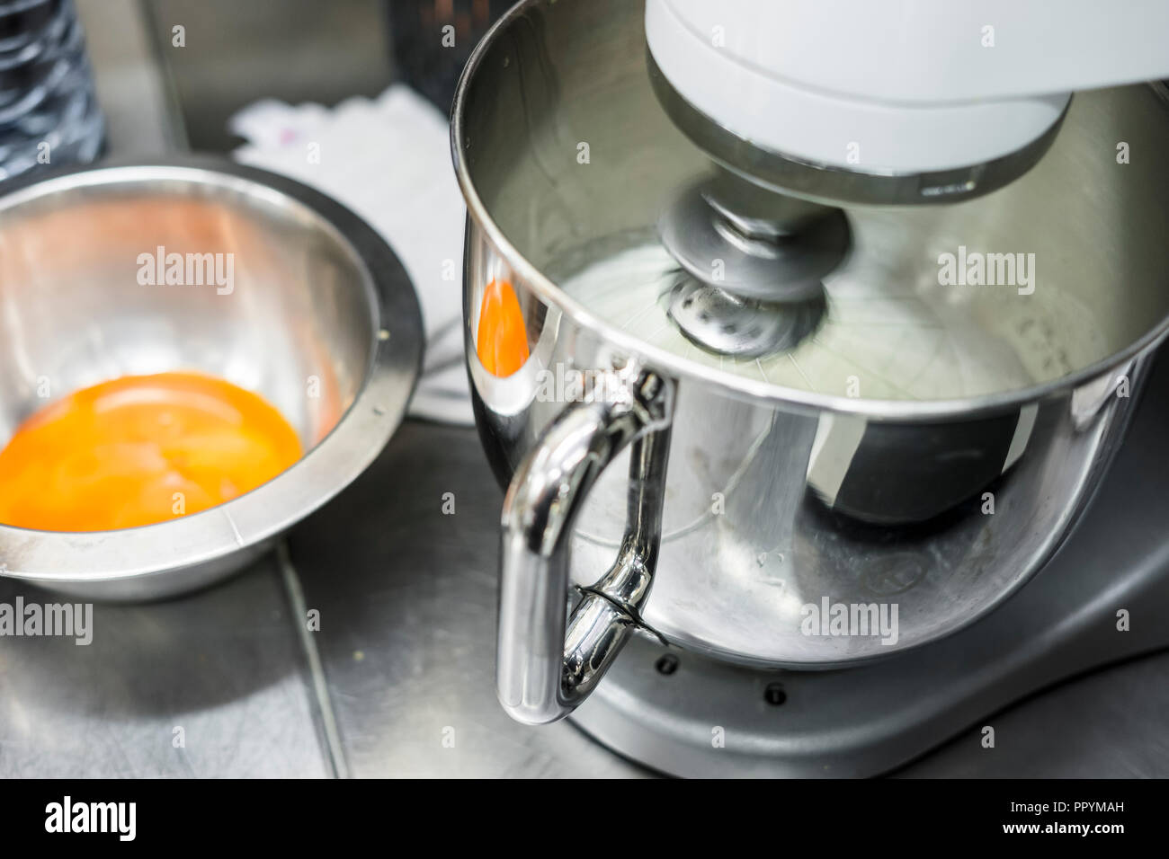 Whipping egg whites in professional kitchen mixer in a restaurant Stock Photo