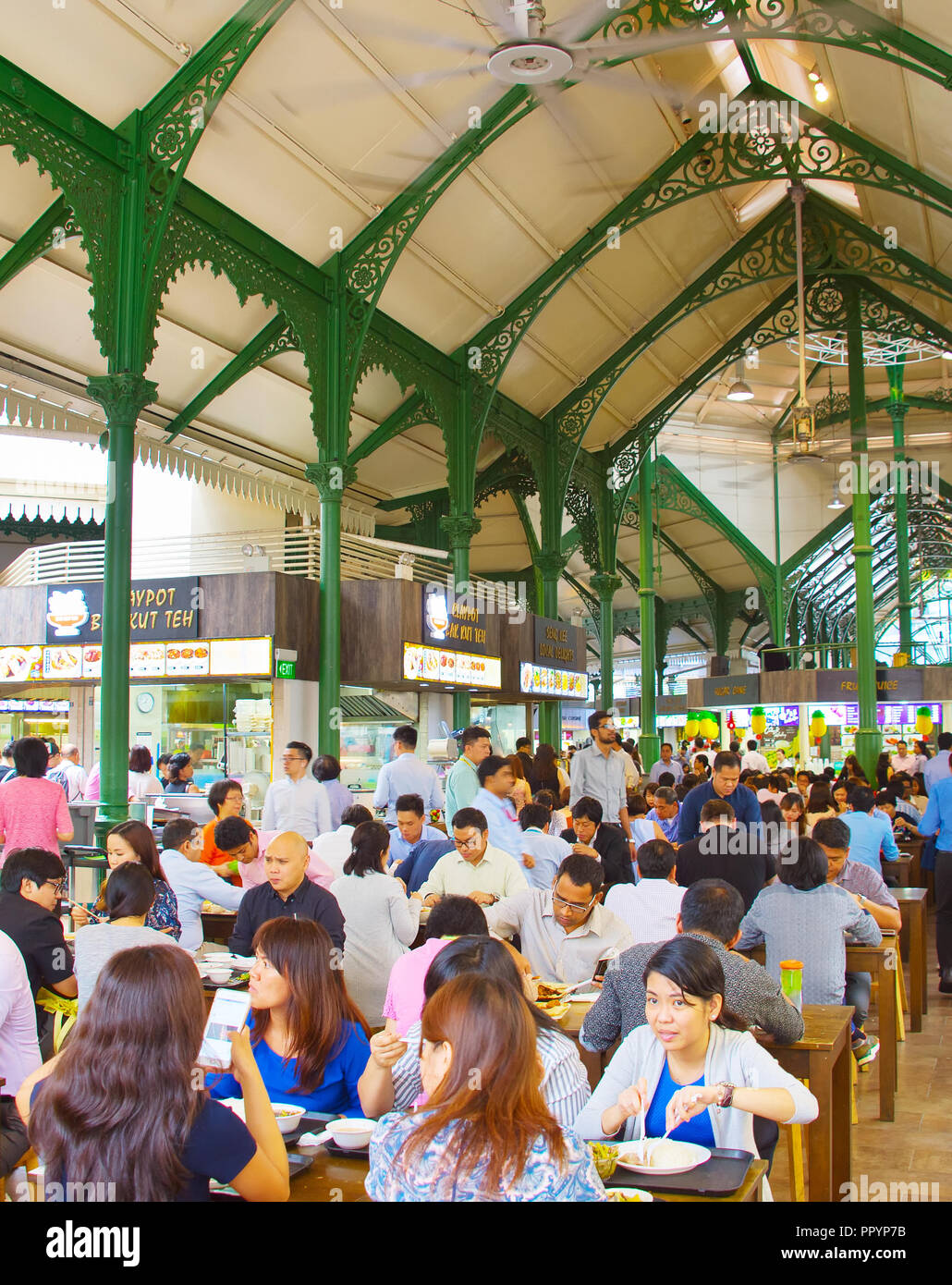 SINGAPORE - JAN 16, 2017 : People at popular food court in Singapore. Inexpensive food stalls are numerous in the city so most Singaporeans dine out a Stock Photo