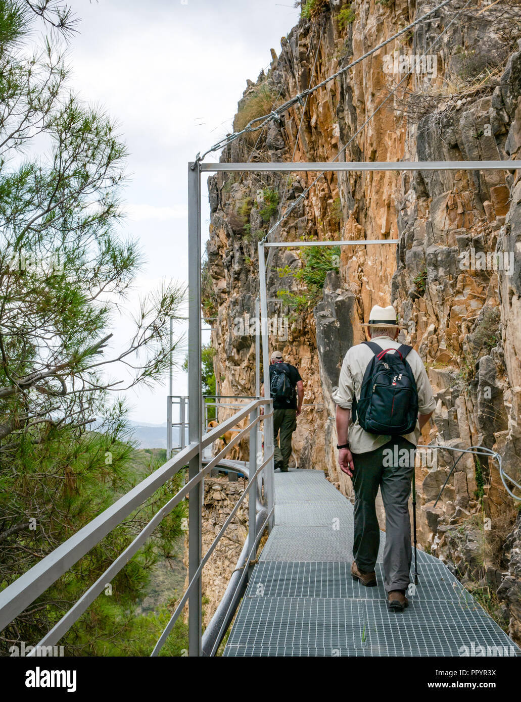Older men walking on mountain gorge cliff metal walkway, Sierras de Tejeda Natural park, Axarquia, Andalusia, Spain Stock Photo