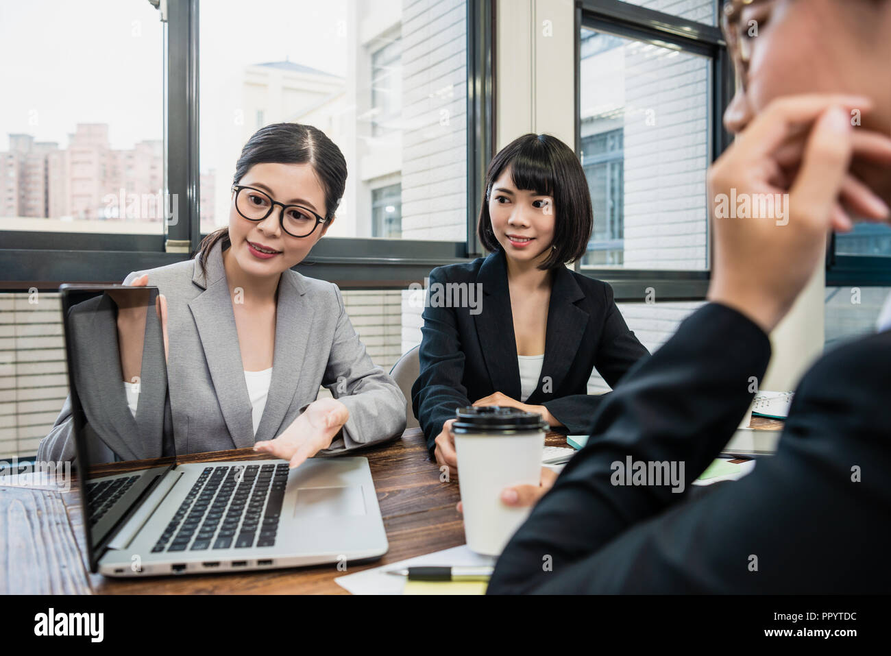 female manager using laptop to show her new project. her colleagues ...