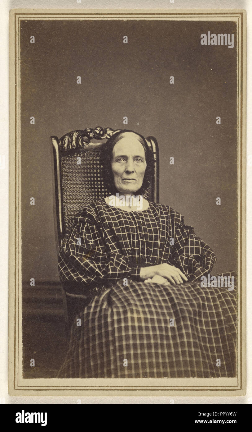 woman wearing a checkered dress, seated in a wicker chair; Abraham F. Burnham, American, active 1880s - 1890s, 1866; Albumen Stock Photo