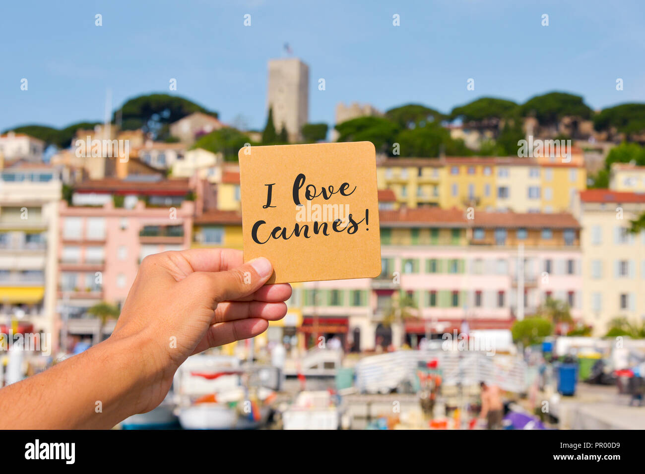 closeup of a young caucasian man holding a brown signboard with the text I love Cannes written in it, in the Vieux Port, the Old Port of Cannes, Franc Stock Photo