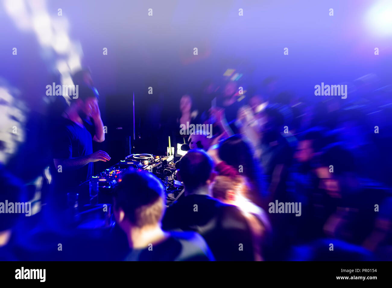 DJ with dj set at night club party. People at the party are having fun on  the background Stock Photo - Alamy