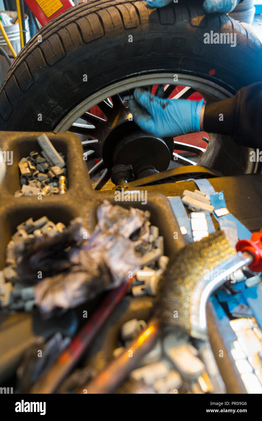 A car rim fitted with a new tyre / tire on a wheel balancing machine ...