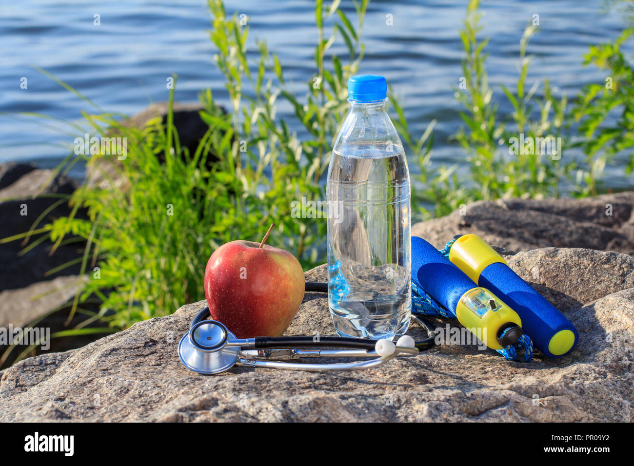 Jump Rope Apple Stethoscope And Bottle With Water On Rock With River Embankment Background Summer Active Lifestyle Stock Photo Alamy