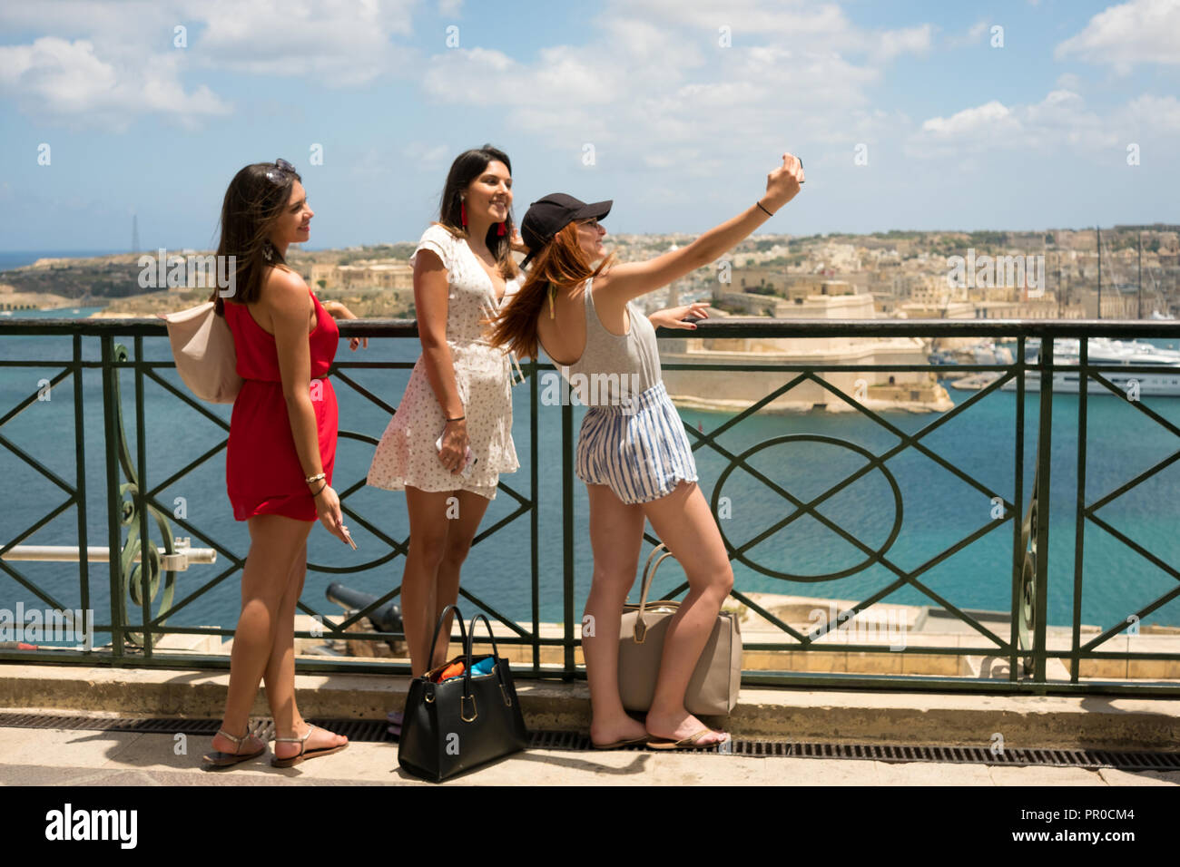 Women take a selfie at the Upper Barrakka Gardens which as a view to the Grand Harbour, in Valleta, Malta. Stock Photo