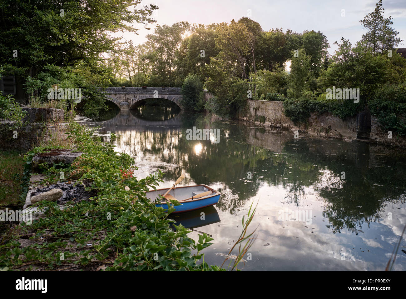 Rowing boat on river with arched stone bridge Stock Photo