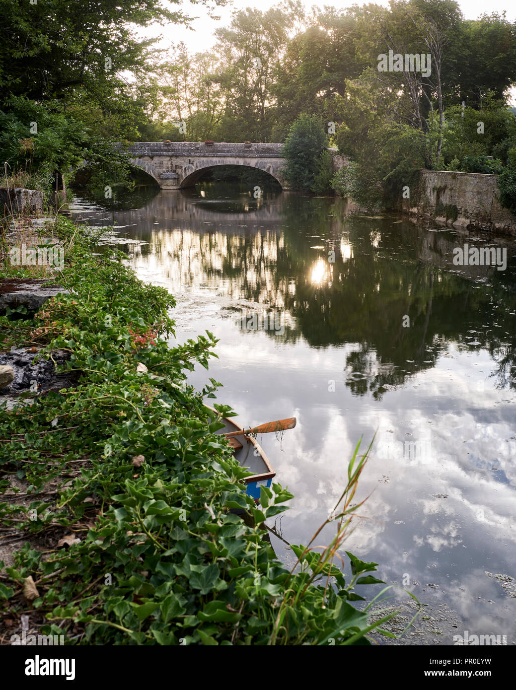 Rowing boat on river with arched stone bridge Stock Photo