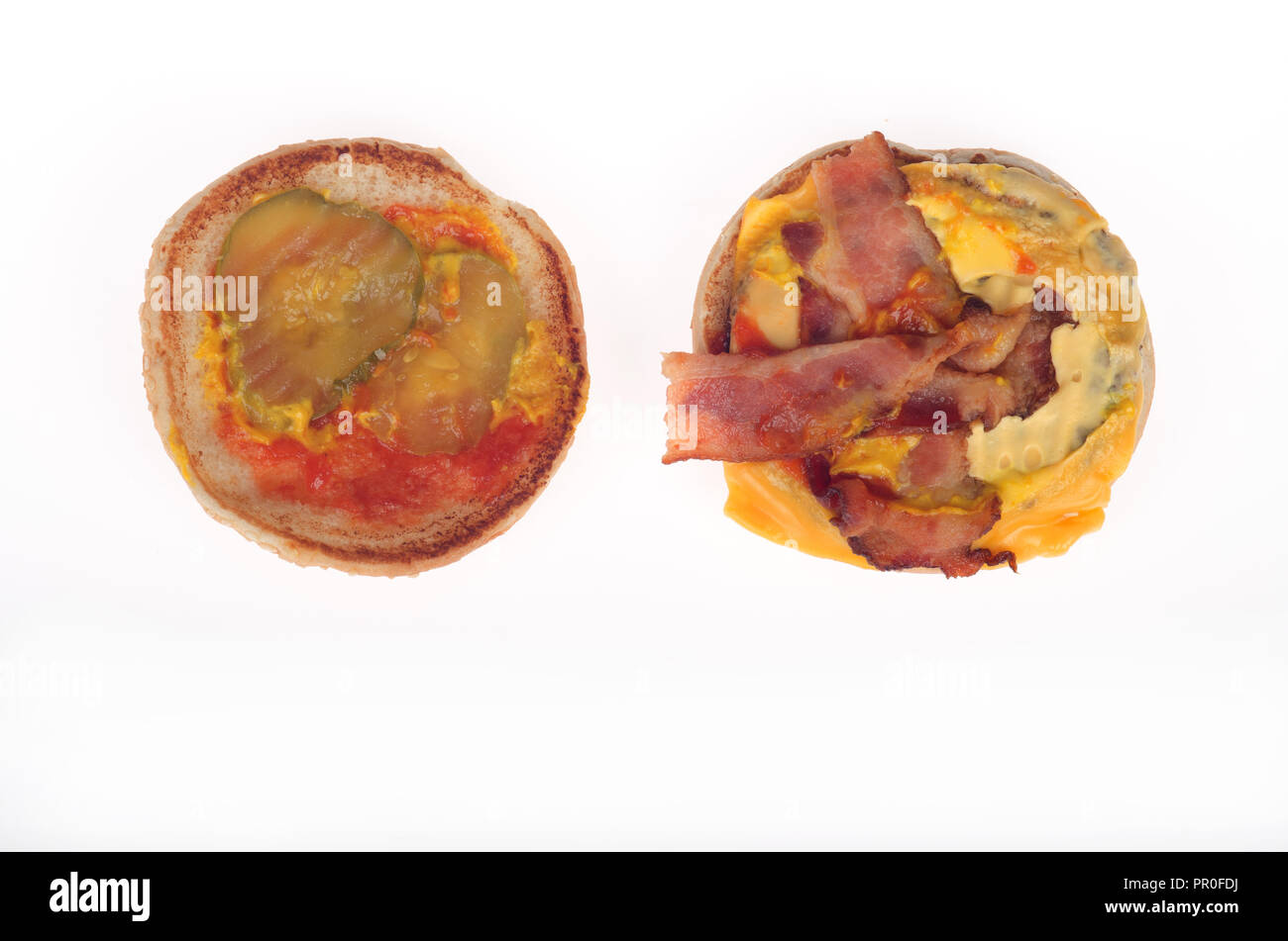 Open bacon cheeseburger showing strips of bacon, yellow american cheese, pickles, ketchup and mustard on bun Stock Photo