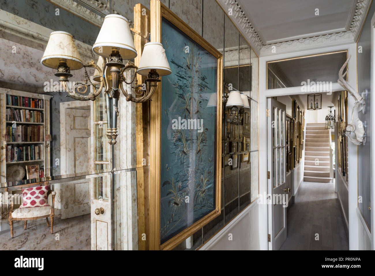 Mirrored hallway entrance with gilt framed embroidery and antique lamps Stock Photo