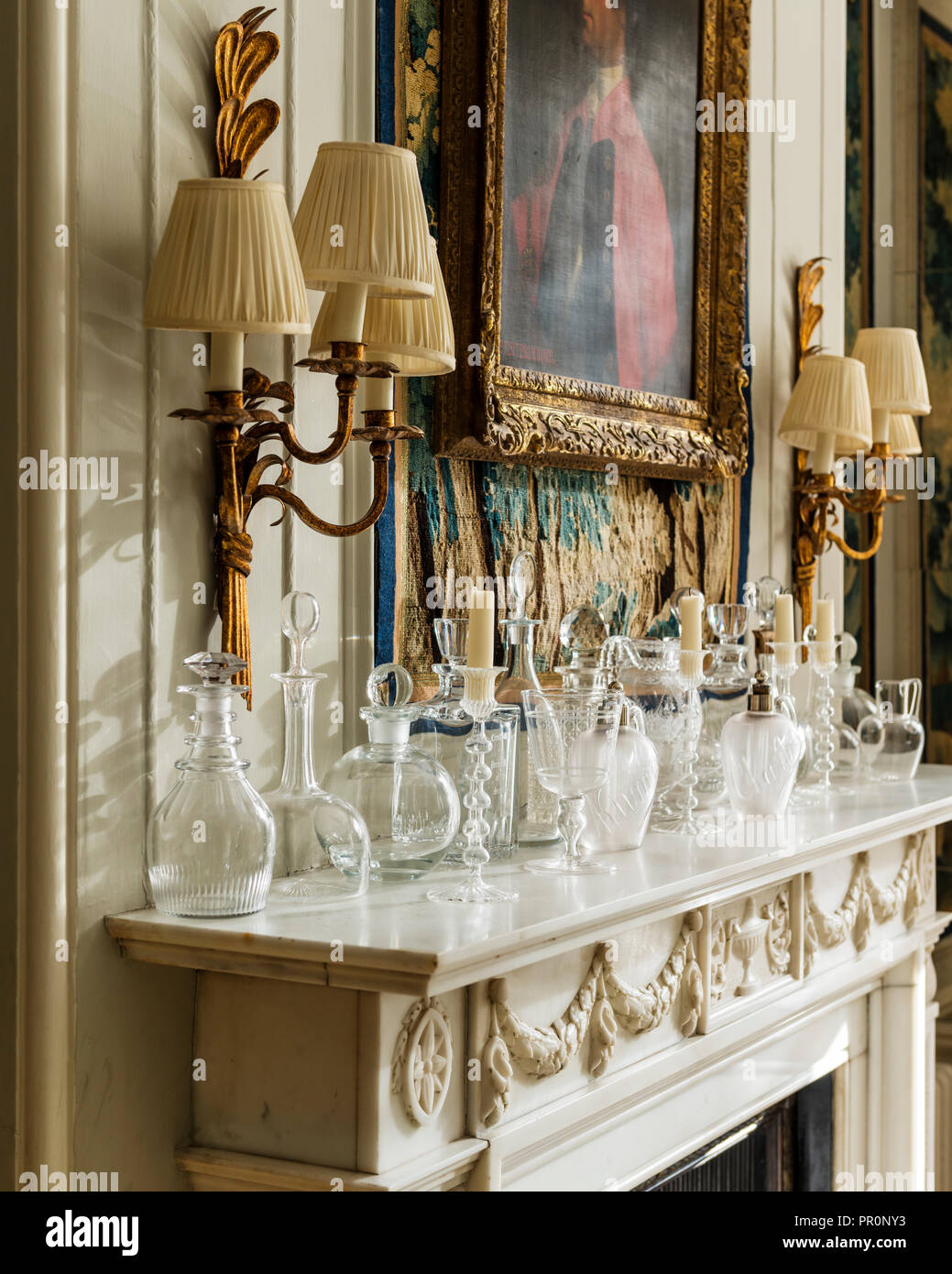Gilt wall lighting with a collection of decanters on mantlepiece Stock Photo