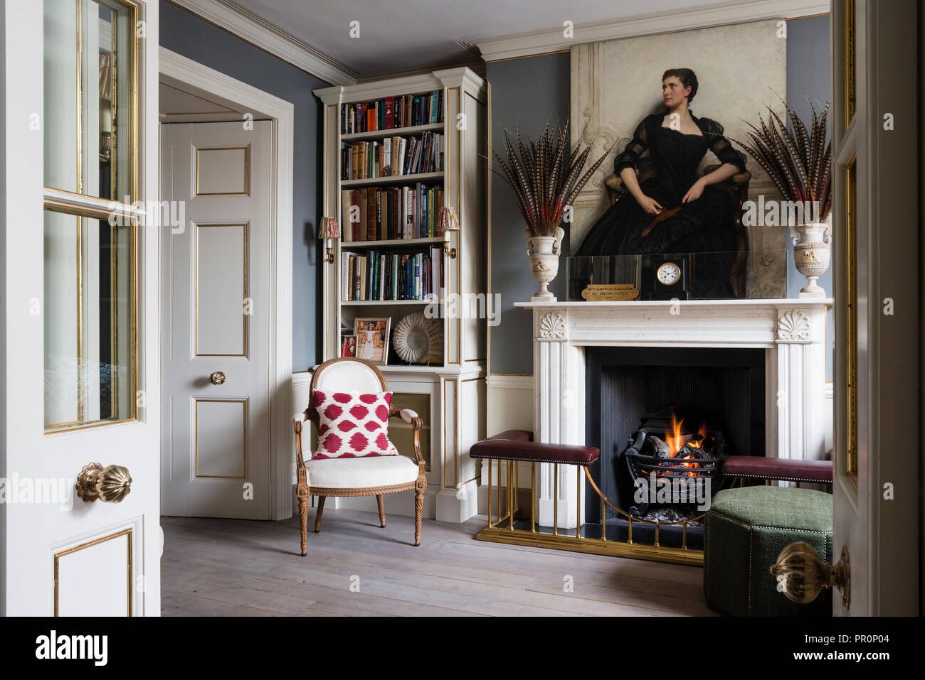 Portarit of Victorian socialite Mrs Sassoon above fireplace with pheasant feathers Stock Photo
