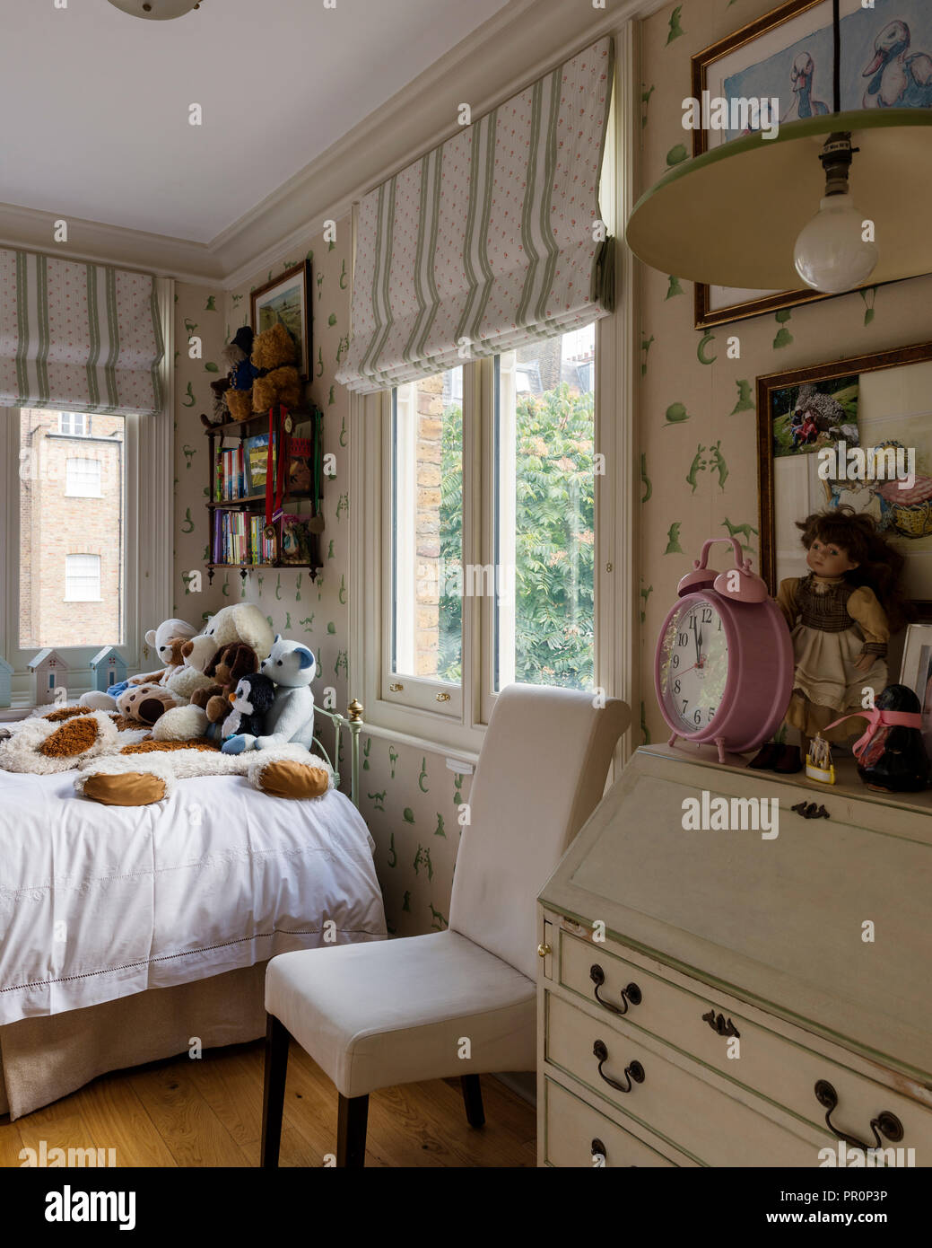 Soft toys on single bed in childs room Stock Photo