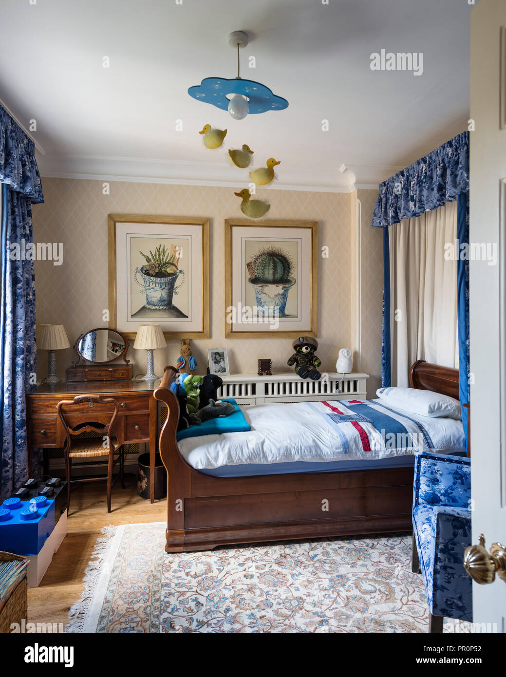 Blue fabrics and vintage wooden sleigh bed in London home Stock Photo