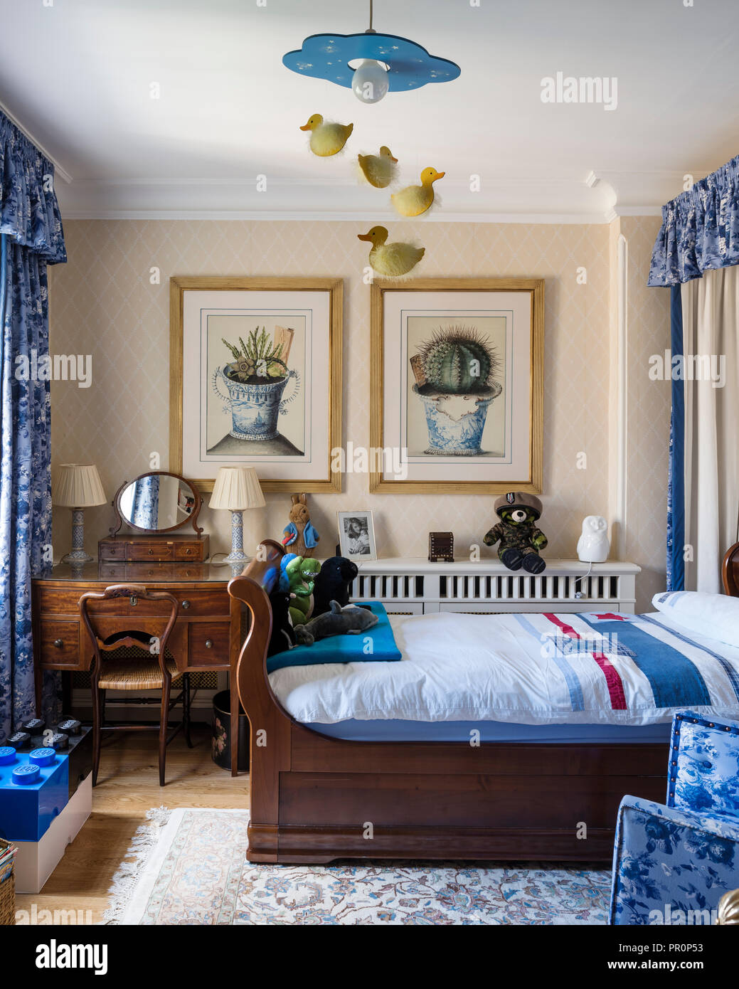 Blue fabrics and vintage wooden sleigh bed in London home Stock Photo