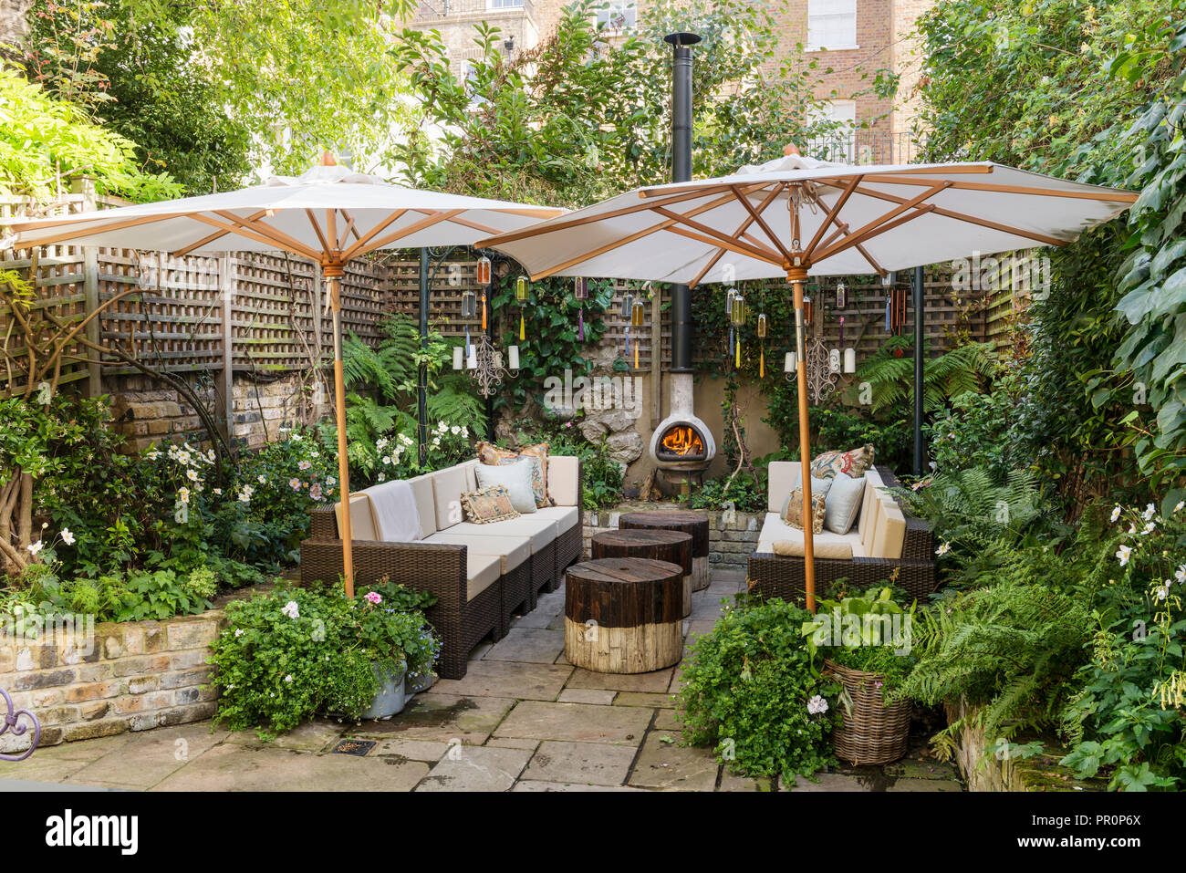 London courtyard garden fenced with trellis in the shade of parasols Stock Photo