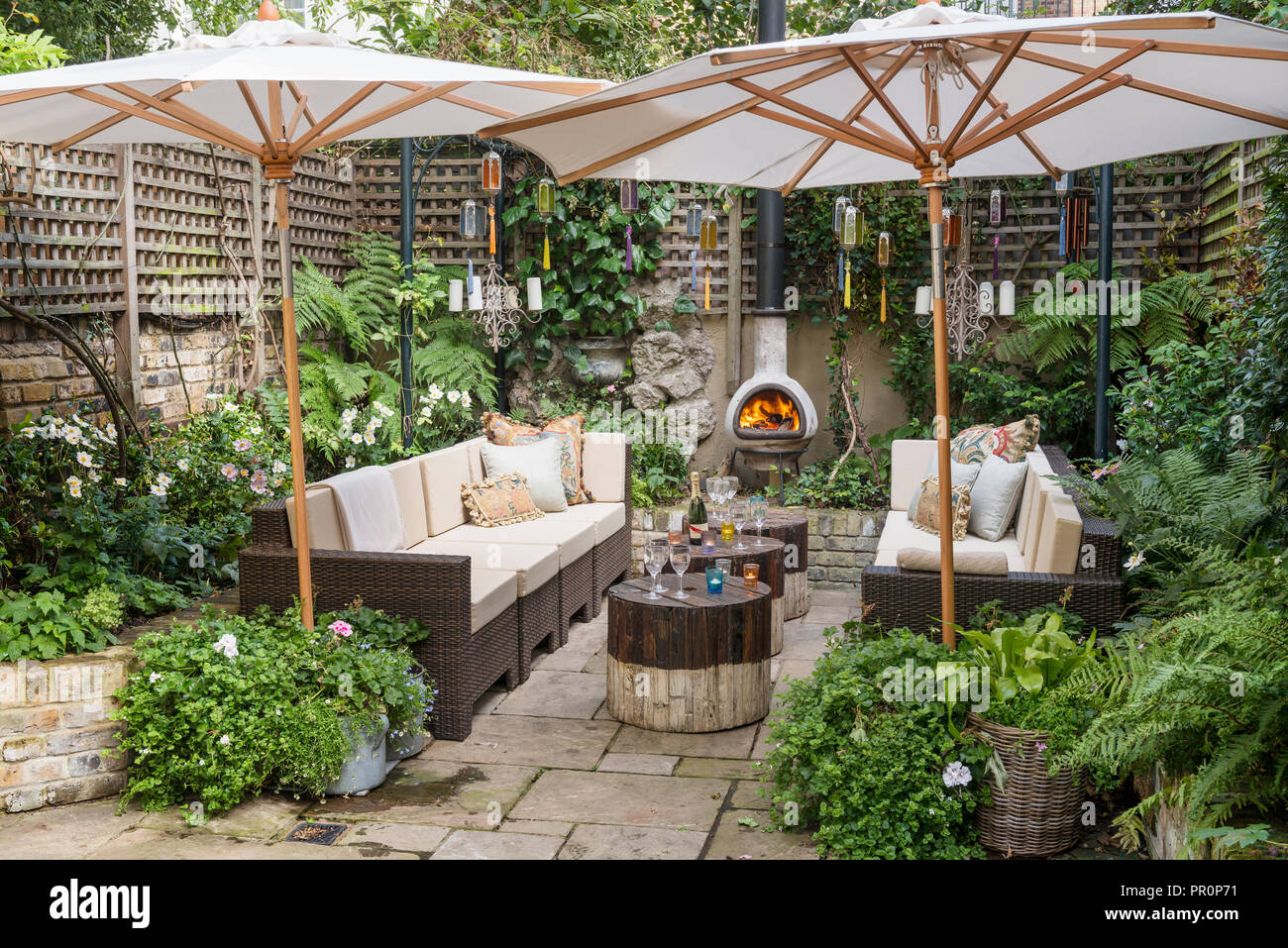 London courtyard garden fenced with trellis in the shade of parasols Stock Photo