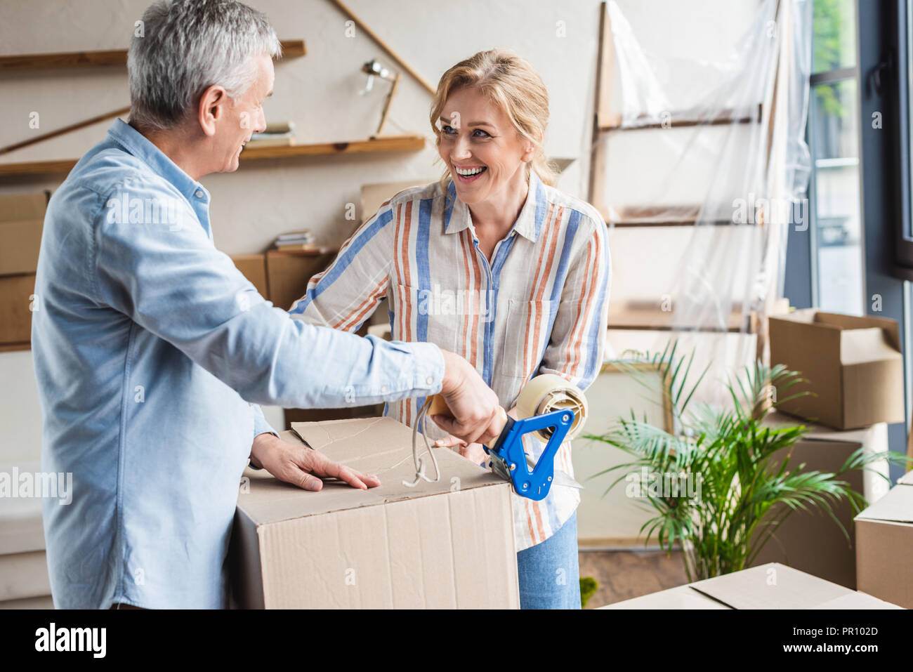 happy elderly couple packing cardboard boxes during relocation Stock Photo
