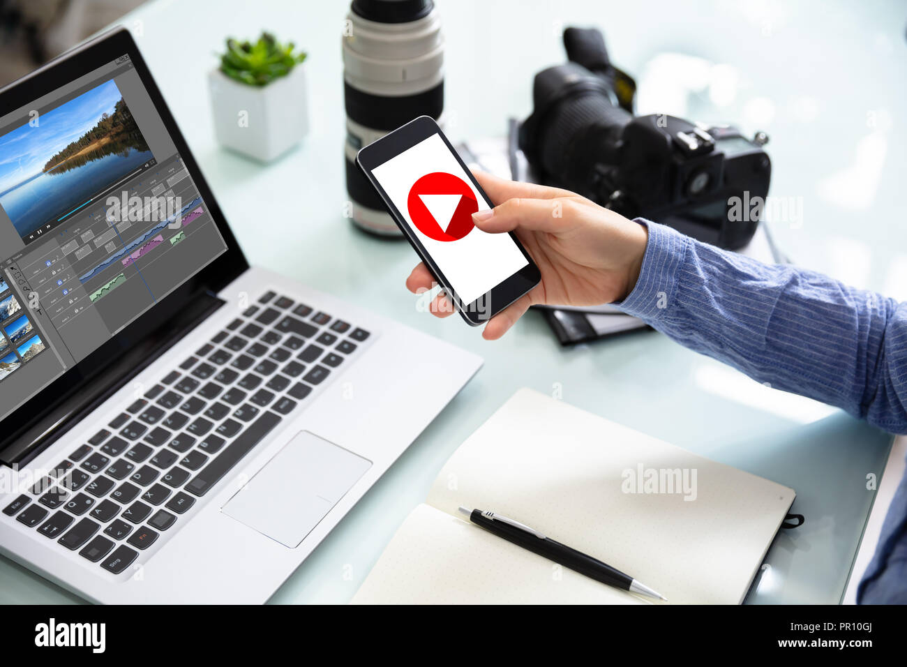 Female Editor Using Cellphone With Play Icon On Screen Stock Photo